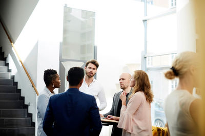 Business people discussing while standing by table in office