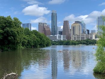 Lake and modern buildings against sky