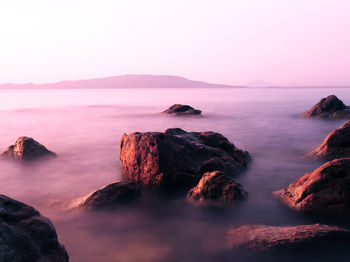 Scenic view of rocks in sea against clear sky