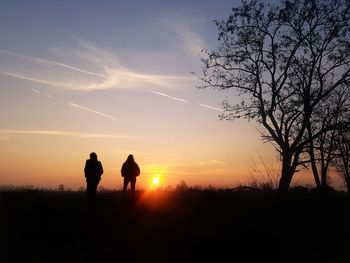 Silhouette people standing on land against sky during sunset