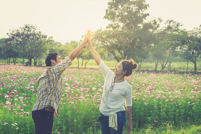 Couple giving high-five while standing by flowering plants