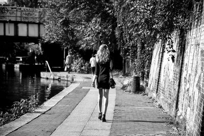 Rear view of woman walking on footpath by canal