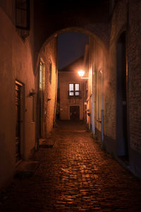 Empty alley amidst buildings at night