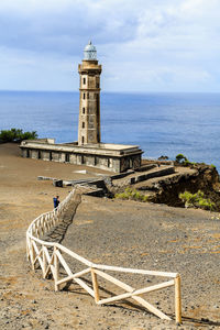 Lighthouse by sea against sky