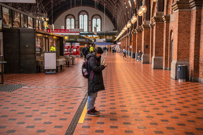 Woman tourist  looks into her smartphone while standing in main hall of copenhagen railway station.