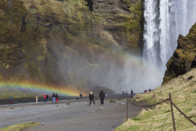 People standing in front of the waterfall admire the power of nature