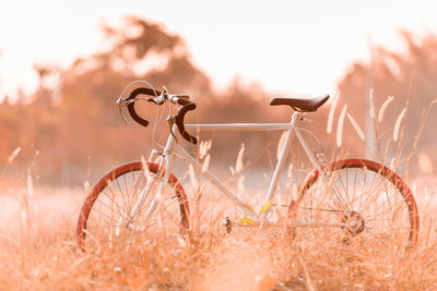 Bicycle parked on field against sky