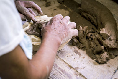 Cropped hands of person molding clay