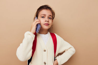 Portrait of young woman standing against pink background