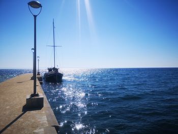 Sailboat in sea against clear blue sky