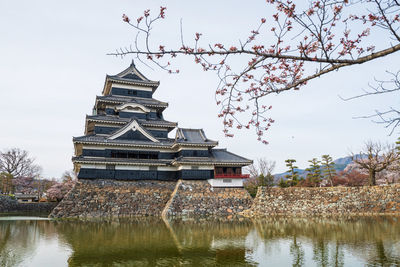 Traditional building by lake against sky