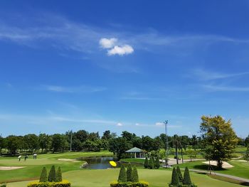 Scenic view of golf course against blue sky