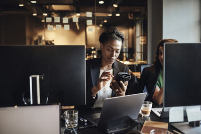 Businesswoman surfing net through smart phone at office