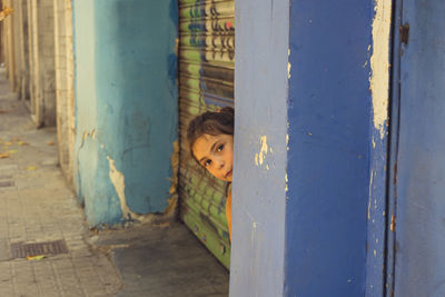 Portrait of girl seen through metal grate