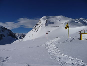 Scenic view of snow covered mountains against blue sky