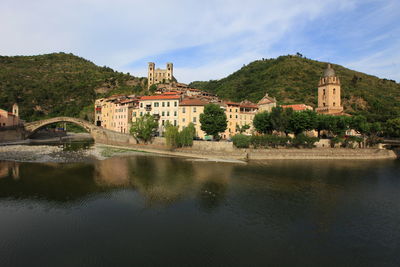 Scenic view of sea by buildings against cloudy sky