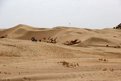 People sitting on desert against sky