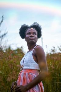 Portrait of young woman looking away while standing on field