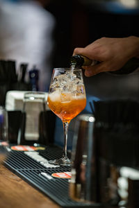 Cropped hand of male bartender pouring alcohol in wineglass at bar