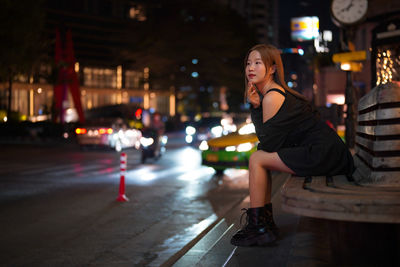 Portrait of young woman standing on street at night