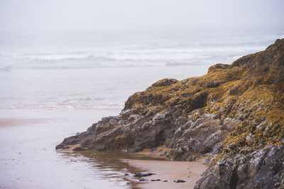 Rock formation at beach against sky