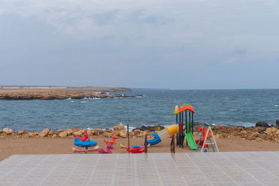 Deck chairs on beach against sky