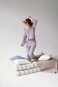 Rear view of woman with arms raised standing against white background