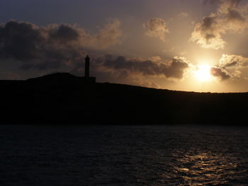 Reflection of silhouette trees in water at sunset