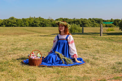 Young woman sitting with basket on field