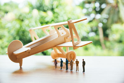 Close-up of toy airplane with figurines on wooden table against trees