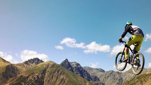 Man riding bicycle on mountain against sky