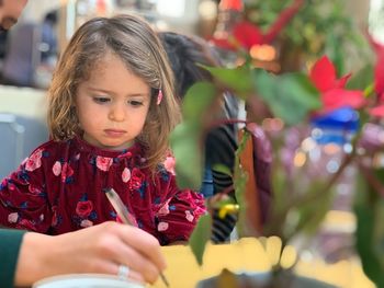 Girl looking at mother writing on paper at home