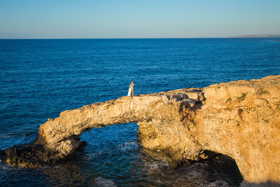 Rock formation in sea against clear blue sky