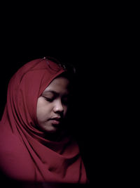 Portrait of young woman against black background