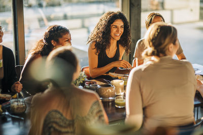 Young woman laughing with female friends during breakfast at retreat center