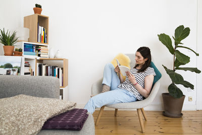 Woman at home sitting on chair reading book