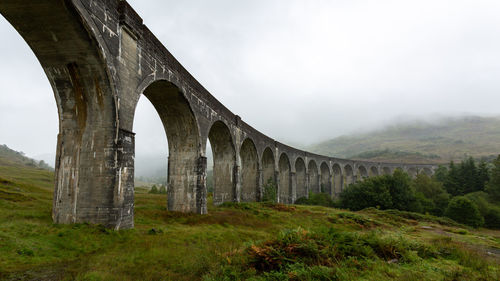 Arch bridge in foggy weather against sky