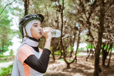 Smiling woman drinking water at park