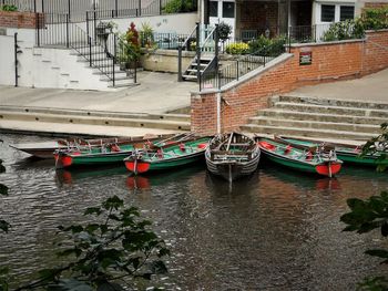 Sailboats moored in sea against buildings in city