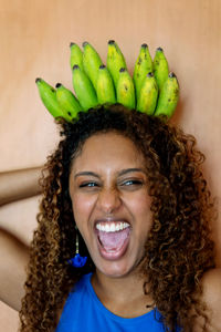 Beautiful african woman with long curly hair smiling holding bunch of bananas as a crown