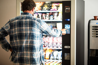 Rear view of man using vending machine