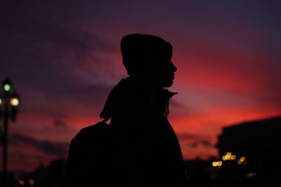 Silhouette woman standing against orange sky