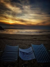 Lounge chairs on beach at sunset