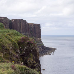 Scenic view of cliff by sea against sky