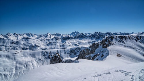 Scenic view of snowcapped mountains against clear blue sky