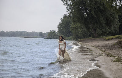 Full length of woman on shore against sky