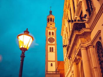 Low angle view of illuminated street light by building against sky