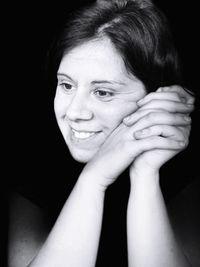 Portrait of smiling young woman against black background