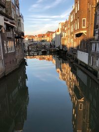 Canal amidst buildings in city against sky