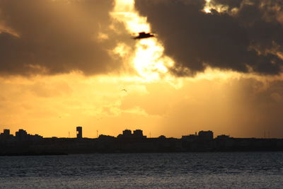 Silhouette buildings against sky during sunset